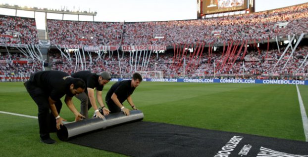 Pracovníci rolujú koberec na ihrisku po odložení odvetného finálového zápasu juhoamerického Pohára osloboditeľov